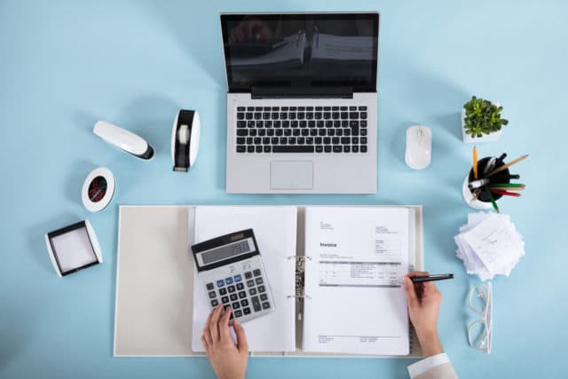 Eine Geschäftsfrau prüft eine Rechnung mit ihrem Taschenrechner